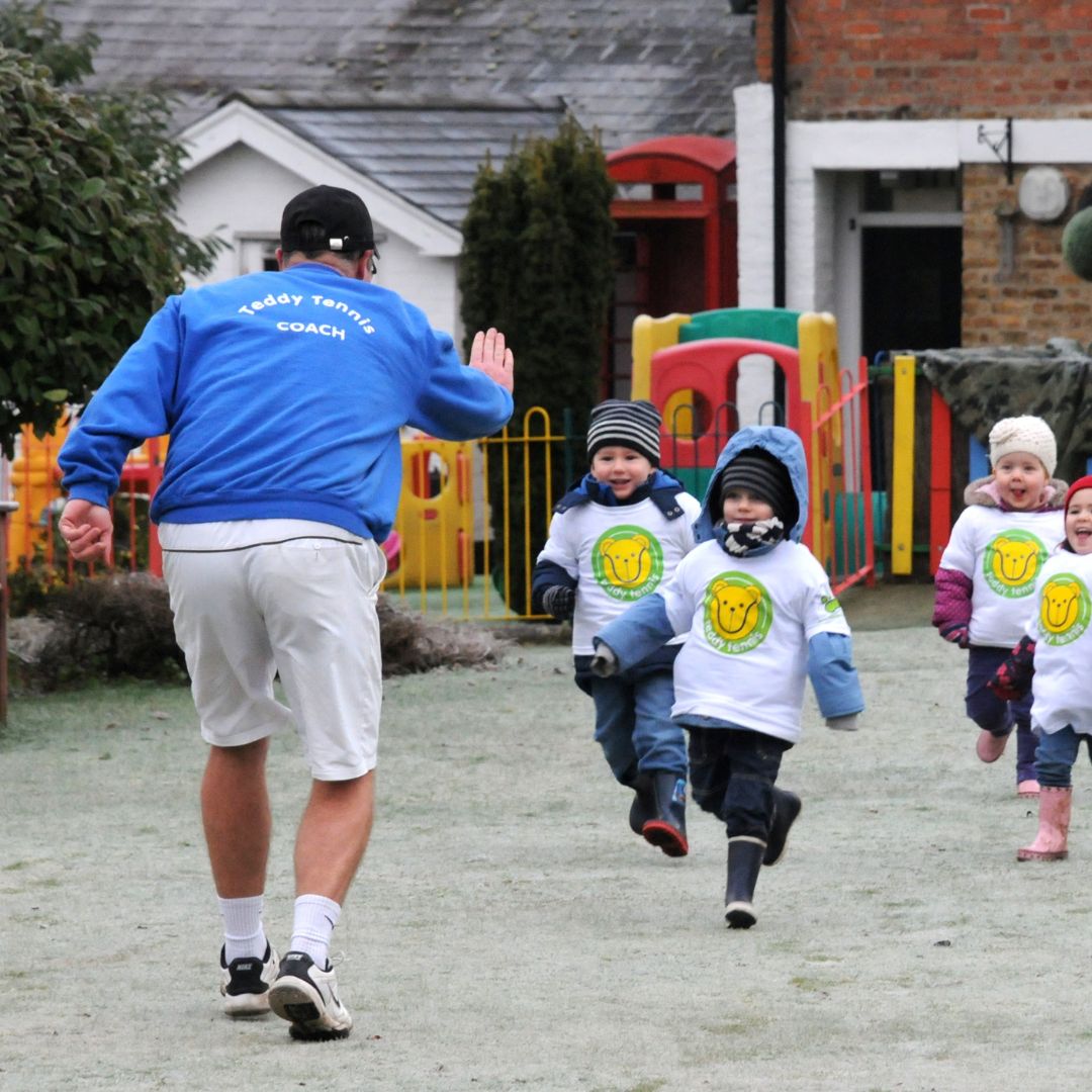 Kids running to high five Teddy Tennis teacher