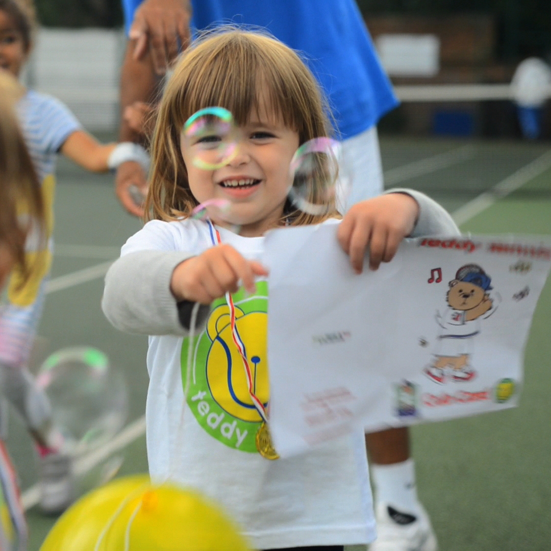 Little girl with bubbles and Teddy Tennis certificate