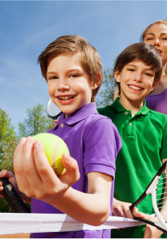 Kids on a tennis court smiling after a Teddy Tennis lesson