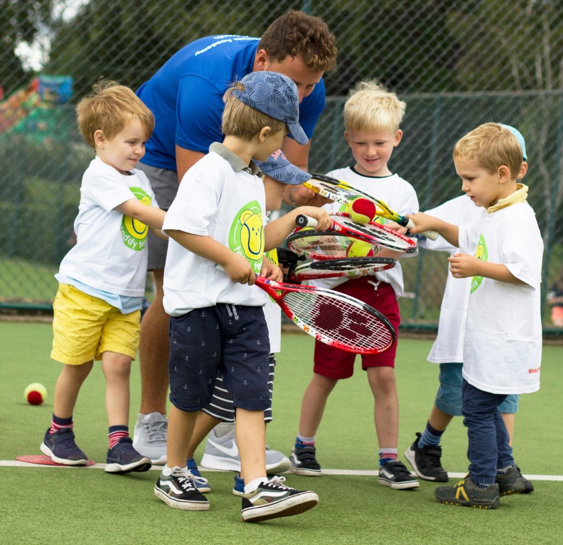 Kids gathered around a teacher for a Teddy Tennis game