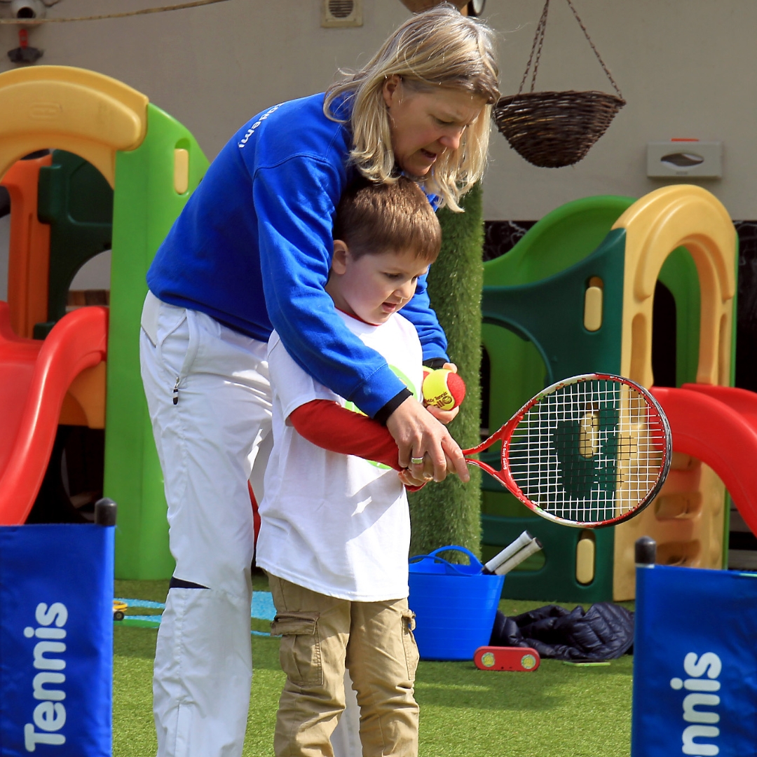 A Teddy Tennis teacher helps correct a child's grip